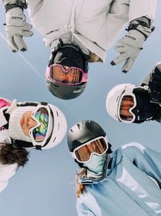 four people wearing skis and goggles standing in a circle