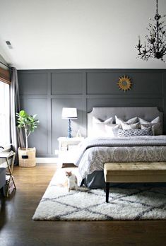 a bedroom with gray walls and white bedding in the center, along with a chandelier hanging from the ceiling