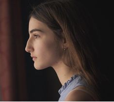 a young woman looking out the window at something in the distance with her eyes closed