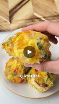 a person is holding up some food on a white and gold plate with the words quiche bites above it