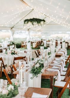 tables and chairs are set up under a tent for an outdoor wedding reception with white linens and greenery