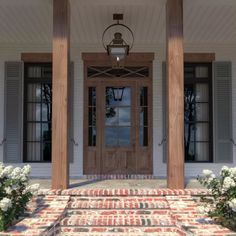 the front porch of a house with flowers on the steps and an entry way leading up to it