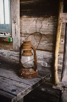 an old lantern sitting on top of a wooden bench in front of a window next to a ladder