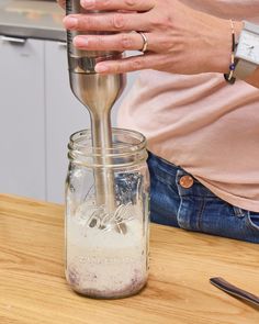 a person pouring something into a glass jar