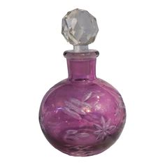 a purple glass bottle with a clear crystal top on a white background in the shape of a flower