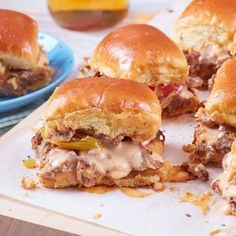 several sliders with meat, cheese and peppers on a cutting board