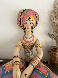 a wooden doll sitting on top of a table next to a potted plant and vase