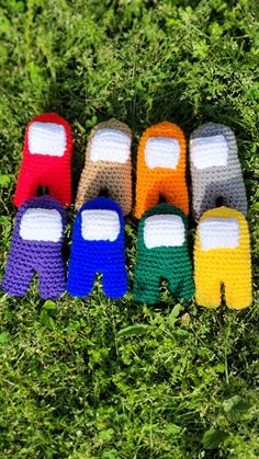 four pairs of colorful knitted shoes sitting on top of green grass in the grass