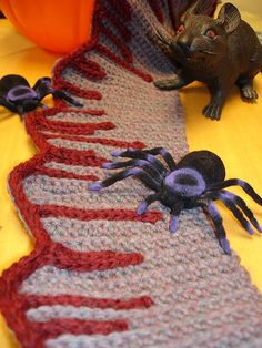 there is a knitted spider on the table next to a toy mouse and pumpkin