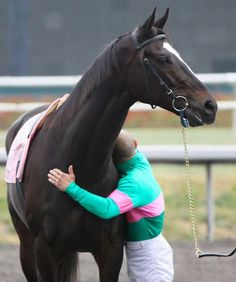 a man is hugging a horse on the track