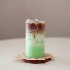 a green and white drink sitting on top of a wooden coaster