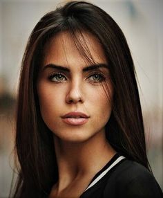 a woman with long brown hair and green eyes is looking at the camera while wearing a black top