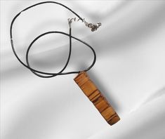 a necklace with a wooden piece hanging from it's end on a black cord