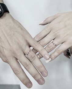 two people holding each other's hands with tattoos on their fingers and one is wearing a watch