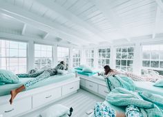 two people laying on their beds in a room with white walls and windows, while another person is lying down