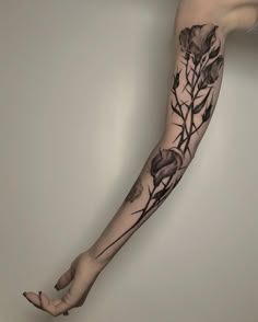 a woman's arm with flowers and leaves on it, as well as her legs