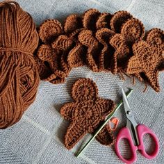 crocheted hearts and yarn are on the floor next to scissors, needles and balls of yarn