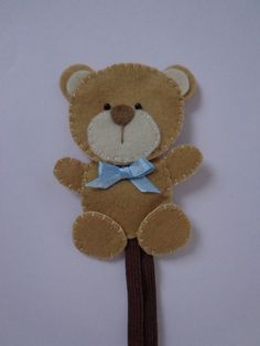 a brown teddy bear with a blue bow on it's head sitting on a stick