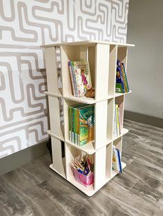 a white book shelf with books on it in front of a wallpapered background