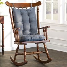 a wooden rocking chair with blue cushion on the seat and backrest, in front of a window