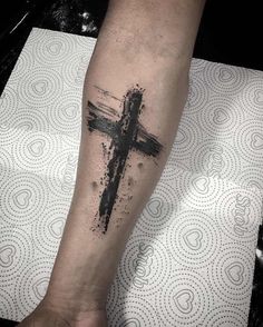 a person with a cross tattoo on their arm