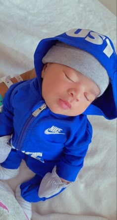 a baby wearing a blue nike jacket and hat