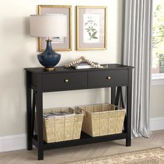 a black console table with two baskets under it and a blue vase on the side