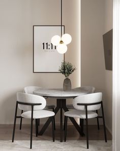 a dining room table with four chairs and a vase on the wall next to it