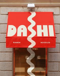 a red sign hanging from the side of a brick building that says dash ramen noodles