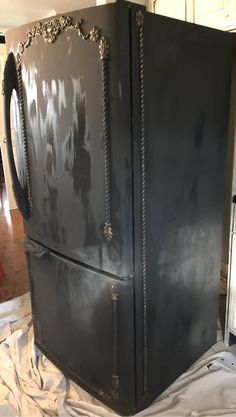 an old black refrigerator is being painted with white paint and silver trimmings on it