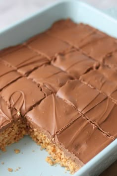 a cake with chocolate frosting cut in half on a blue plate and ready to be eaten