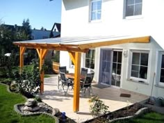 a patio with a table and chairs under an awning next to a white house