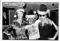 black and white photograph of three people wearing christmas hats