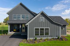 a large gray house sitting on top of a lush green field