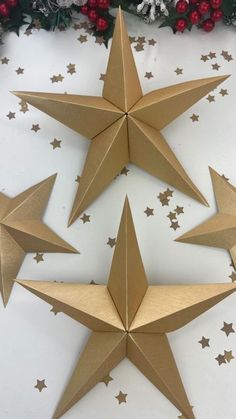 three gold stars on a white table with christmas decorations