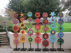 a group of colorful paper flowers sitting on top of a white wall next to a green field