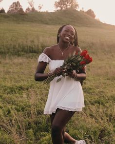 a woman standing in a field holding flowers