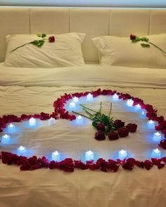 a heart shaped bed with roses and candles in the shape of a heart on it