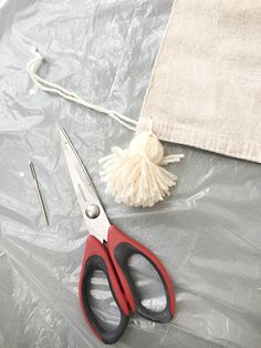 a pair of red scissors sitting on top of a table next to a white towel