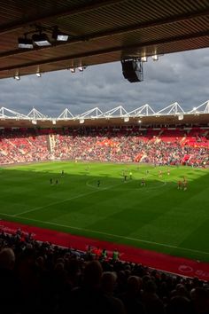 a large stadium filled with lots of people on top of a soccer field and fans in the stands