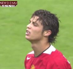 a young man standing on top of a soccer field wearing a red and white uniform