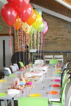 a long table with many balloons and confetti on it