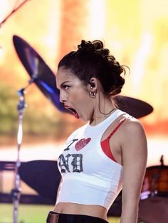 a woman with her mouth open standing in front of a drum set and microphones