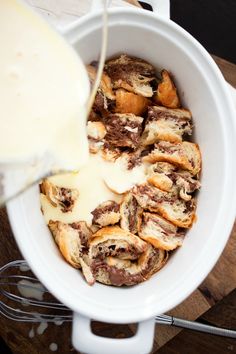 someone pouring milk into a bowl filled with pastries