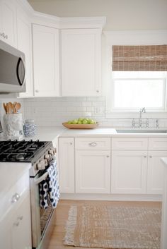 a kitchen with white cabinets and wooden floors