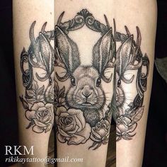 a rabbit and roses tattoo on the legs with an ornate frame around it, which is surrounded by flowers