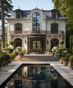 a large white house with lots of windows and plants in front of the pool area