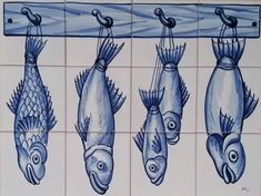 four fish hanging on a tile wall in blue and white