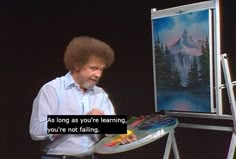 a man is standing in front of an easel with a painting on it that says, as long as you're learning, you're not falling