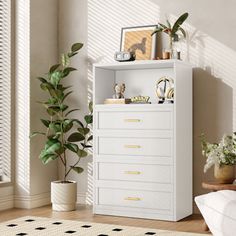 a living room with white furniture and potted plants on top of the dressers